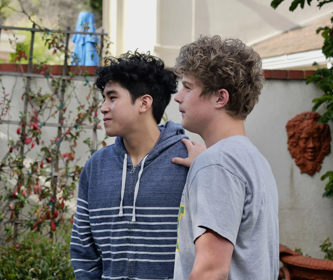 Elan with a younger teammate's hand on his shoulder, talking together outdoors